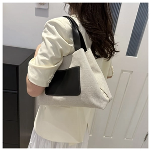Detailed view of casual canvas bucket bag with black leather pockets shown on model