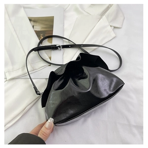 Close-up of black glossy pleated cloud bag with adjustable strap and silver metal details