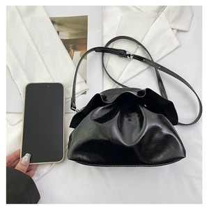 Size comparison of a black cloud crossbody bag next to a smartphone showing mini dimensions