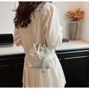 Detailed view of light blue drawstring bucket bag with floral pattern and pearl handle