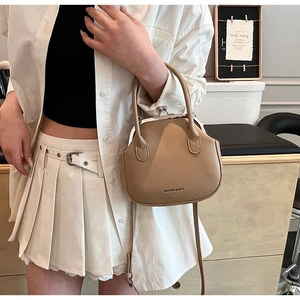 Khaki vintage kiss-lock bag with top handle and crossbody strap styled on a model