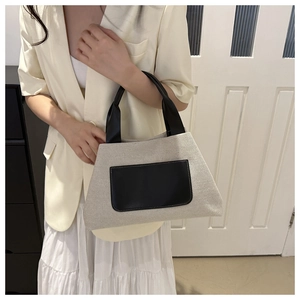 Detail of canvas bucket bag with black leather pockets and straps on model