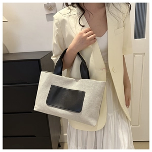 Detail view of stylish canvas tote bag with contrast black pocket and shoulder straps