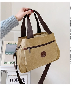 Dettaglio borsa tote in tela kaki con manici marroni e toppa logo in pelle frontale