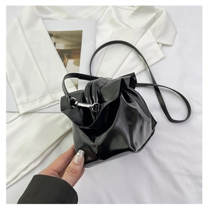 Close-up of black glossy patent leather pleated cloud bag with silver metal clasp