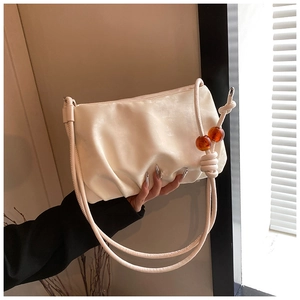 Detalle de bolso nube fruncido beige con cuentas de ámbar en la correa trenzada