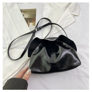 Close-up of black glossy drawstring cloud bag with adjustable strap and wrinkled texture