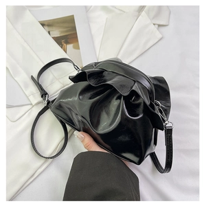 Close-up of black pleated cloud bag with shiny finish and thin shoulder strap