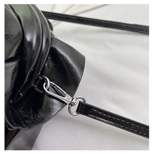 Detail of silver metal hook and sleek black glossy leather strap with clean stitching