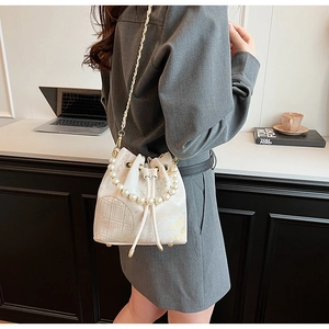 Detail of cream drawstring bucket bag with pearl handle and vintage floral print
