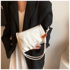 Detalle del bolso nube plisado crema con correa de cuerda y elegantes cuentas de ámbar
