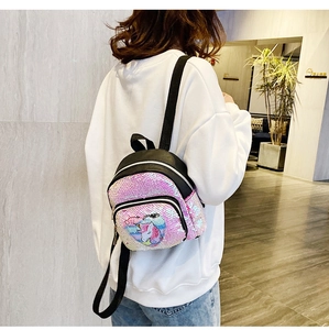 Vista laterale di una ragazza con uno zaino a forma di unicorno con paillettes rosa