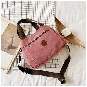 Dettaglio della borsa tote vintage in tela con patch logo in pelle e tracolla regolabile