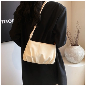 Detalle del bolso nube plisado crema combinado con un blazer negro en escena minimal