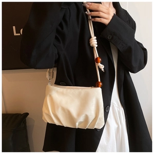 Detalle del bolso nube plisado crema con cuentas de ámbar y textura de cuero suave