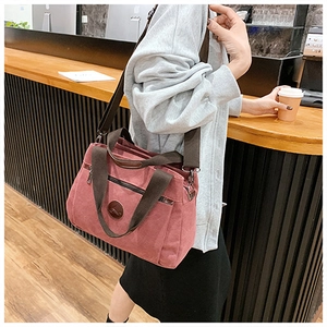 Vista dettagliata della borsa in tela rosa polvere con manici marroni in un caffè