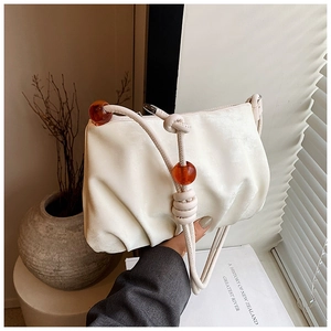 Detalle del bolso nube crema con cuentas de ámbar y correa de hombro de cuerda anudada