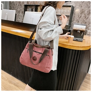 Borsa in tela rosa cipria con doppi manici e tracolla in una calda atmosfera da caffè