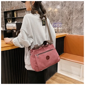 Dettaglio borsa tote vintage in tela rosa con tracolla marrone regolabile e logo