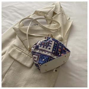 Detail of woven bohemian bucket bag showing cream leather base and gold metal studs
