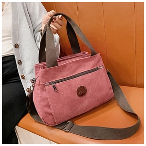 Dettaglio della borsa tote in tela rosa con tasca frontale con zip e manici marroni