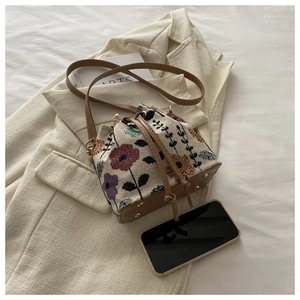 Detail of embroidered bucket bag with leather base and protective metal studs