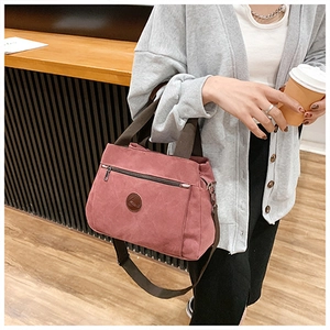 Dettaglio della borsa in tela rosa con trama del tessuto e manici marroni in stanza