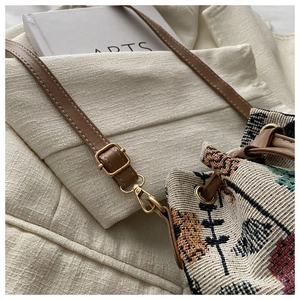 Detail of colorful ethnic woven bucket bag featuring premium leather straps and metal hardware