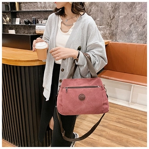 Borsa a tracolla in tela rosa antico tenuta da una modella in un caffè moderno