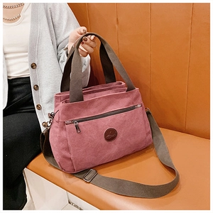 Dettaglio della borsa vintage in tela rosa con manici marroni e logo in pelle