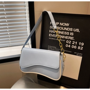 Detail van lichtblauwe baguette-tas met golvende flap en gouden kettingband