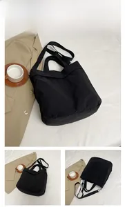Détail d'un grand sac cabas noir avec bandoulière réglable et texture unie élégante
