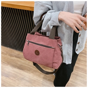 Dettaglio della borsa vintage in tela rosa con tasca zip e logo in pelle marrone