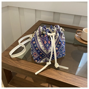 Detail view of woven bucket bag with geometric patterns on a wooden coffee table