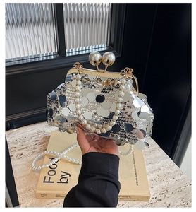Detailed close-up of silver sequin evening clutch bag with pearl handle and metal clasp