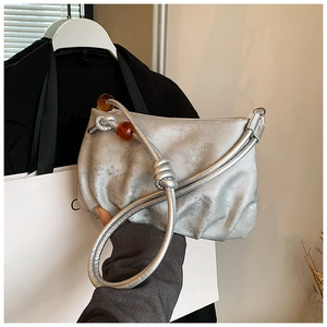 Detalle del bolso nube plisado plateado con asa de cuerda y cuentas de resina ámbar