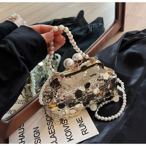 Close-up of gold sequin evening clutch bag with pearl clasp and chain straps