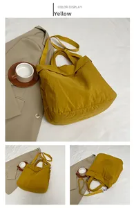 Détail d'un grand sac cabas jaune en nylon avec bandoulières réglables et poignées