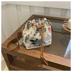 Dettaglio borsa a secchiello ricamata a fiori con coulisse in pelle e finiture dorate