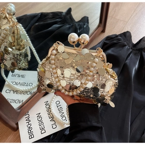 Detailed close-up of sequined evening bag with large pearl clasp and luxury chain