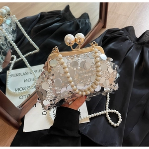 Detailed close-up of a silver sequin evening bag featuring large pearl clasp and handle