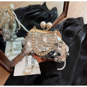 Macro shot of silver sequin evening bag with gold frame and large pearl clasp detail