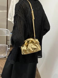 Metallic gold ruched cloud bag with adjustable shoulder strap worn by a model