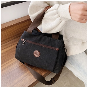 Dettaglio della borsa tote in tela nera vintage con tracolla regolabile e logo in pelle