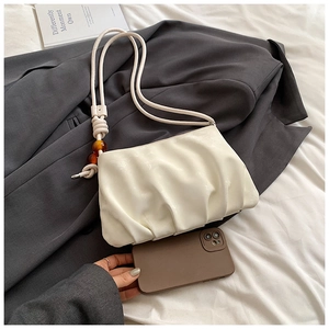 Detalle del bolso nube plisado blanco con cuentas de ámbar y textura de piel sintética suave