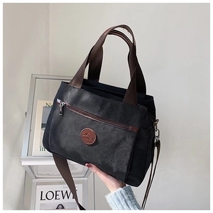 Vista dettagliata della borsa tote in tela nera con manici marroni e logo in pelle