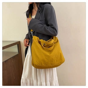 Grand sac cabas en toile jaune avec bandoulière réglable porté par un mannequin femme