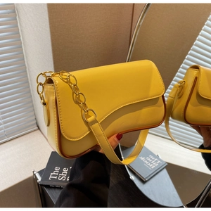 Detail van een felgele PU-leren tas met goudkleurige ketting en verfijnde bruine randen
