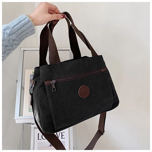 Dettaglio della borsa in tela nera con tasca con cerniera e patch logo in pelle rotonda
