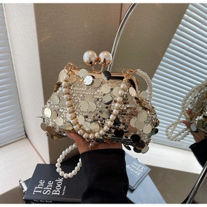 Detail view of champagne gold sequins, pearl handle, and twin pearl clasp on evening clutch